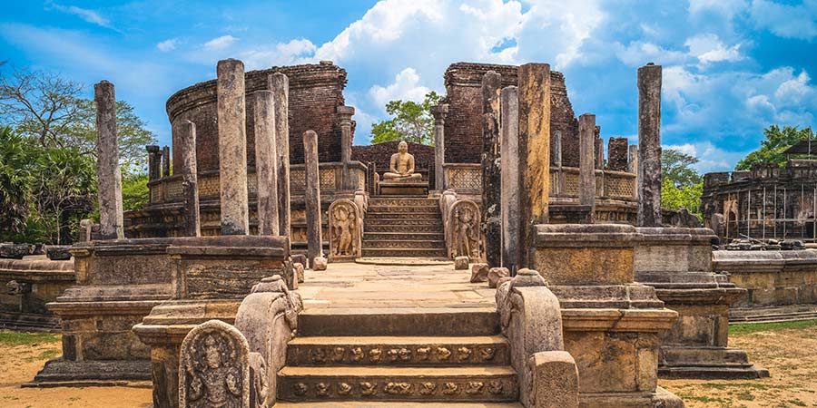 A stone Buddha sits in the middle of the crumbling ancient city of Polonnaruwa in Sri Lanka. 